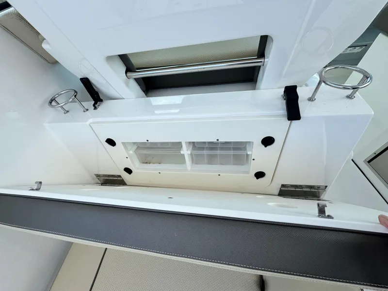 Slide: The Image of 2019 Pursuit DC 325 Dual Console boat interior with storage compartment and cup holders. - 16