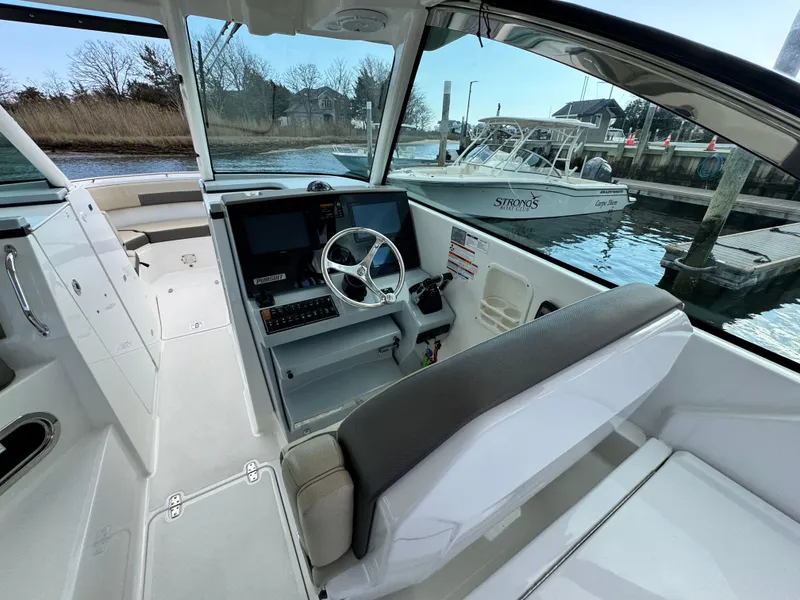 Slide: The Image of 2019 Pursuit DC 325 Dual Console boat interior with steering wheel and dock view. - 22