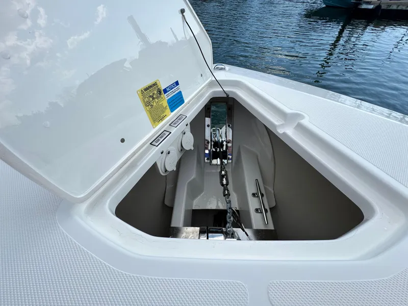 Slide: The Image of 2019 Pursuit DC 325 Dual Console anchor compartment open by the water. - 33