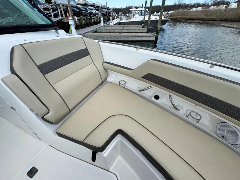 Slide: The Image of 2019 Pursuit DC 325 Dual Console boat interior with beige seating, docked at marina. - 34