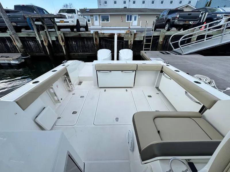 Slide: The Image of 2019 Pursuit DC 325 Dual Console boat interior at dock, featuring spacious seating and storage. - 38