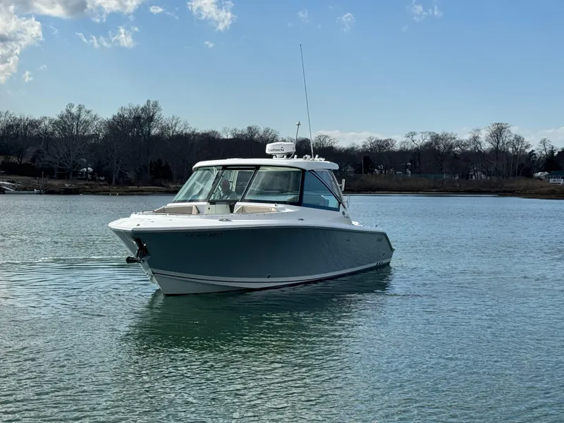 Slide: The Image of 2019 Pursuit DC 325 Dual Console boat on calm water under blue sky. - 4