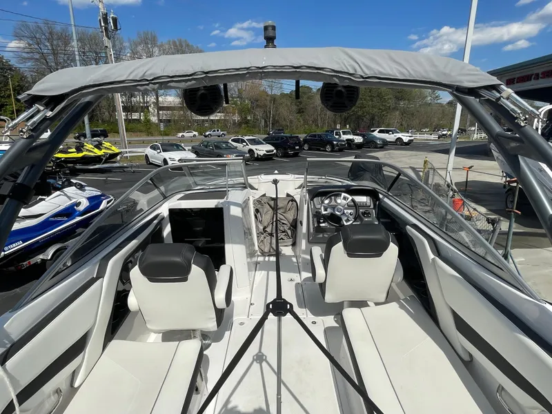 Slide: The Image of 2015 Yamaha Boats AR240 High Output interior with seating and dashboard, parked outdoors. - 9
