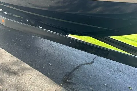 Slide: The Image of 2021 Centurion Ri265 boat trailer on pavement, partial view, with green grass in background. - 11