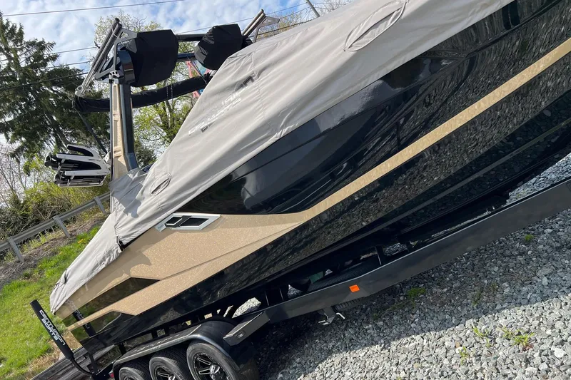 Slide: The Image of 2021 Centurion Ri265 boat on trailer, covered, parked on gravel. - 3