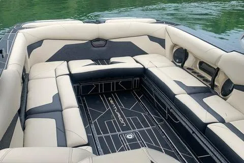 Slide: The Image of 2021 Centurion Ri265 boat interior with beige and black seating, on a lake. - 5
