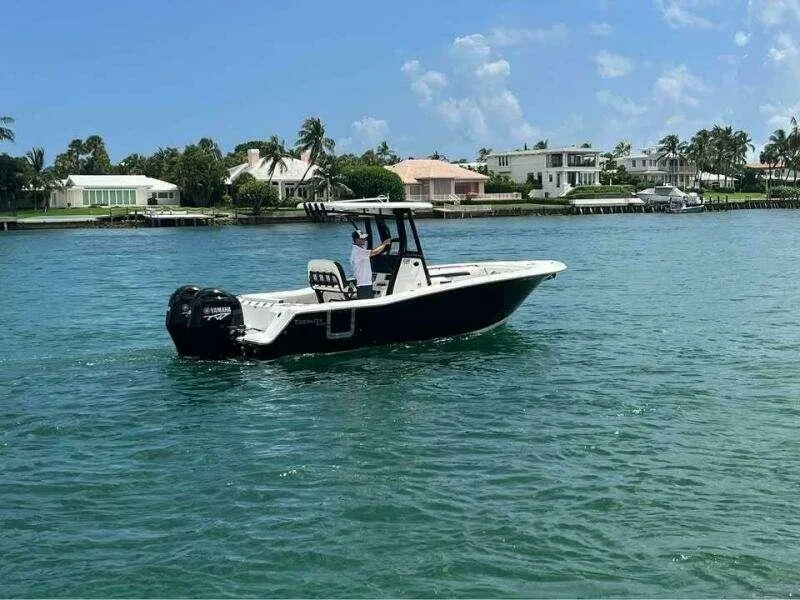 Slide: The Image of 2023 Tidewater 256 CC Adventure boat cruising on a sunny day near waterfront homes. - 10