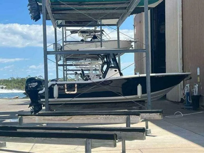 Slide: The Image of 2023 Tidewater 256 CC Adventure boat in storage, featuring a Yamaha outboard motor. - 13