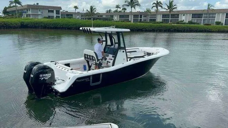 Slide: The Image of 2023 Tidewater 256 CC Adventure boat on water, near waterfront homes, with dual Yamaha engines. - 6