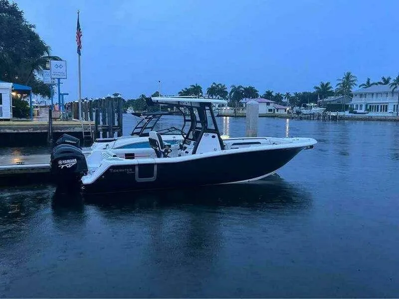 Slide: The Image of 2023 Tidewater 256 CC Adventure boat docked in a serene marina setting. - 8