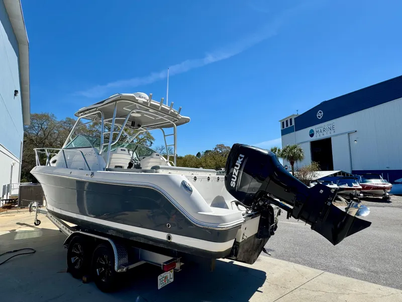 Slide: The Image of 2015 Robalo R245 Walkaround boat with Suzuki outboard motor, parked near a marine facility. - 4