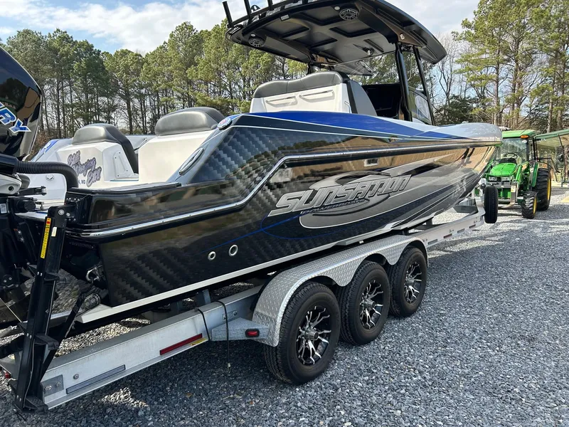 Slide: The Image of 2020 Sunsation 32 CCX boat on trailer, black and blue design, parked outdoors. - 2
