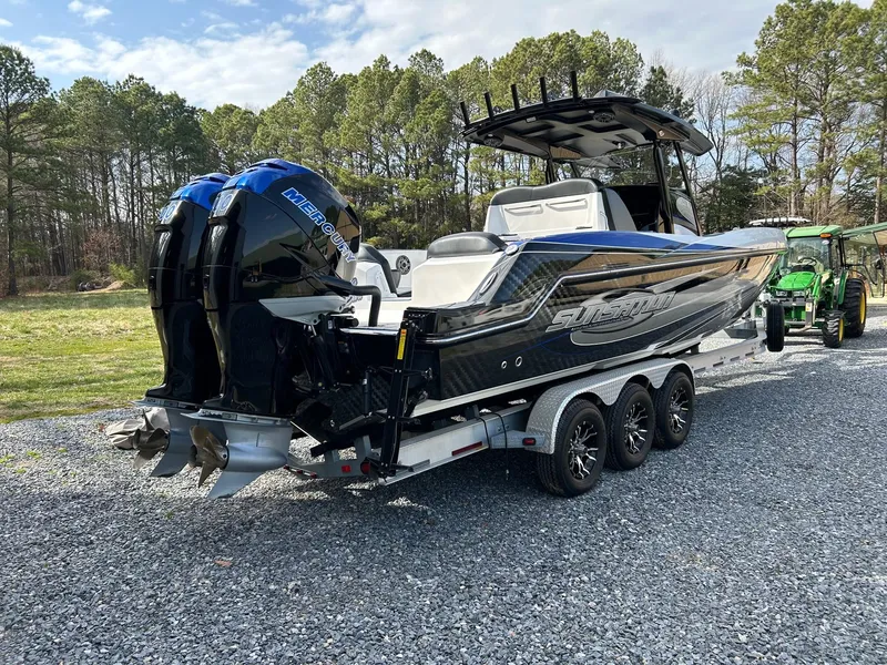 Slide: The Image of 2020 Sunsation 32 CCX boat on trailer, dual engines, parked on gravel, surrounded by trees. - 4