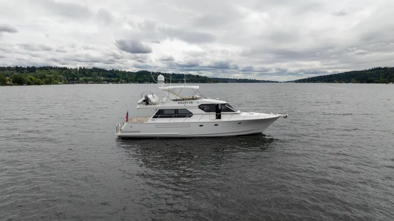 Slide: The Image of 2001 West Bay 58 RPH yacht on a calm lake under cloudy skies. - 2