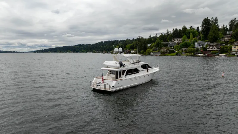 Slide: The Image of 2001 West Bay 58 RPH yacht on a serene lake with cloudy skies and lush shoreline. - 3