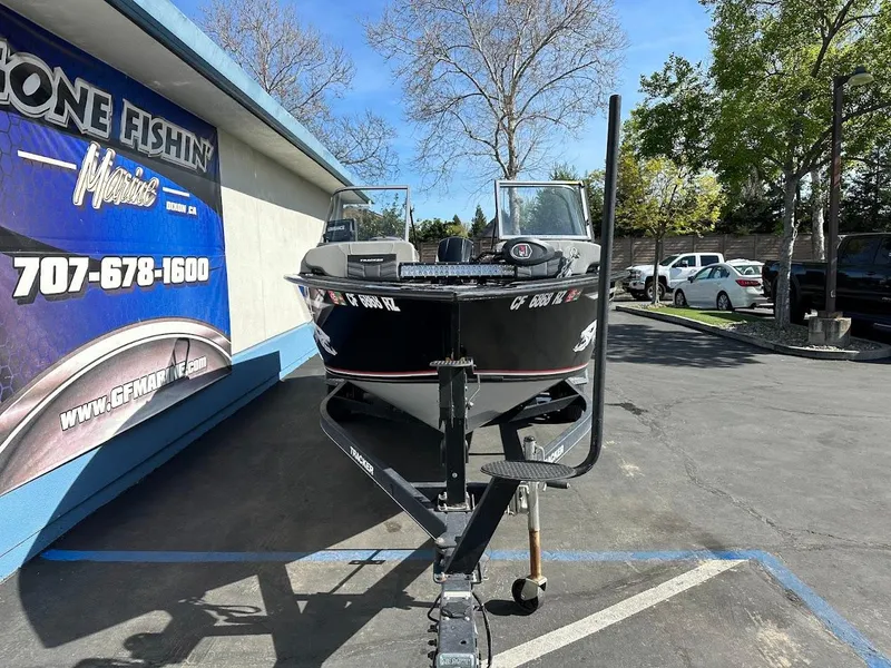 Slide: The Image of 2018 Tracker Targa V-19 WT boat on trailer, parked outdoors near a fishing store. - 2