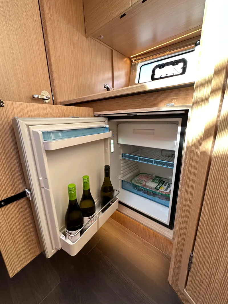 Slide: The Image of Compact fridge in 2023 Bavaria SR36 yacht, stocked with wine bottles and frozen goods. - 47