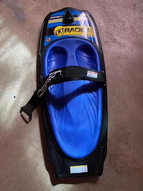 Slide: The Image of O'Brien Radica kneeboard with blue seat and adjustable strap on concrete floor. - 25