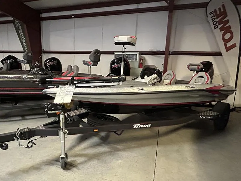 Slide: The Image of 2023 Triton 179 TrX bass boat displayed indoors on a trailer. - 0