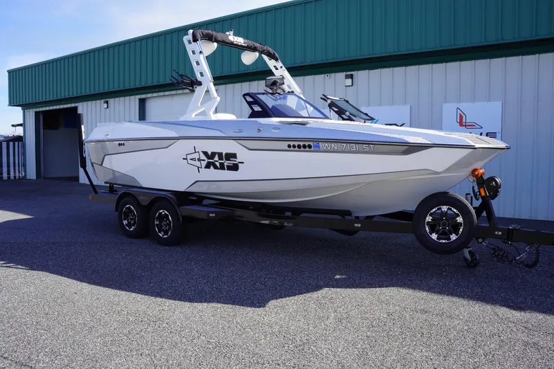 Slide: The Image of 2019 Axis A22 boat on trailer, parked outside a green-roofed building. - 2