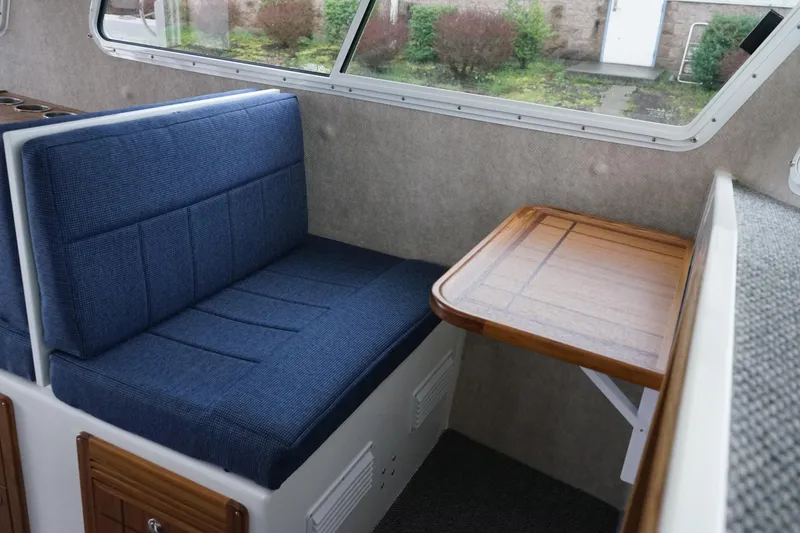Slide: The Image of Interior of 2025 Sea Sport 26' Aleutian with blue seating and wooden table. - 11