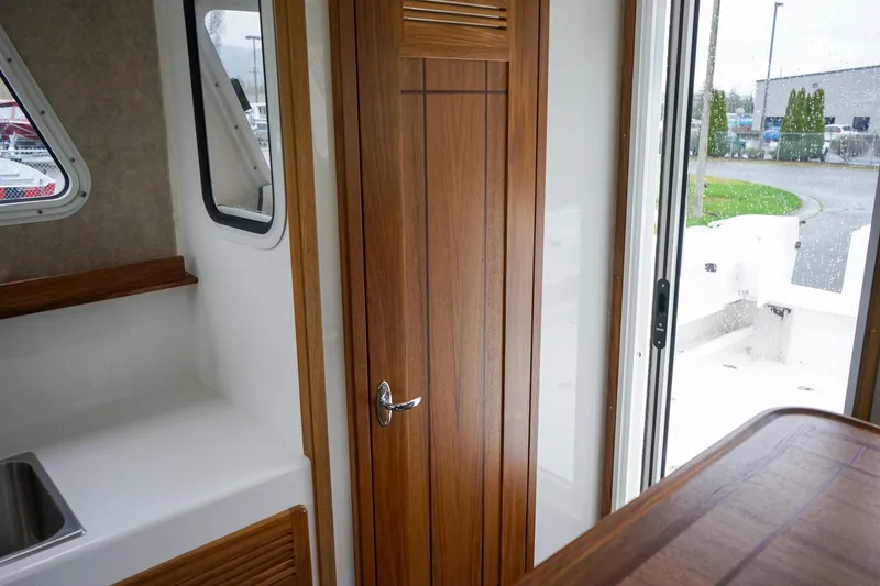 Slide: The Image of Interior view of 2025 Sea Sport 26' Aleutian boat, featuring wooden door and window. - 16