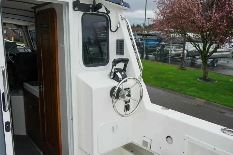 Slide: The Image of 2025 Sea Sport 26' Aleutian boat helm with steering wheel, docked near blooming tree. - 5