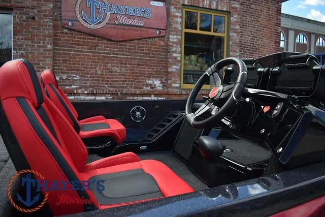 Slide: The Image of 2024 Ikon Boats LX21 interior with red seats and steering wheel, parked at Thayer's Marina. - 10