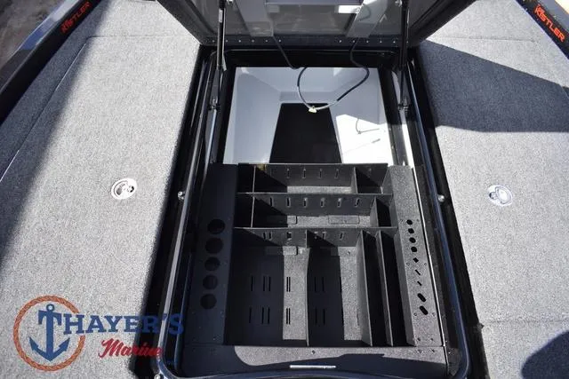 Slide: The Image of 2024 Ikon Boats LX21 storage compartment with organized tackle trays and carpeted deck. - 22