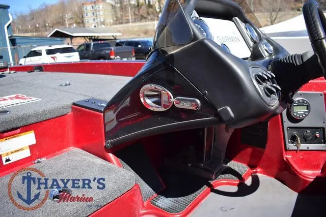 Slide: The Image of 2021 Triton 18 TrX boat dashboard with Garmin system, red interior, and Thayer's Marine logo. - 18