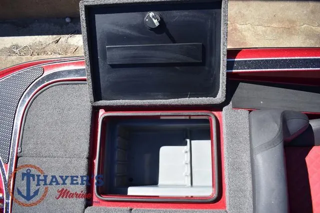 Slide: The Image of Open storage compartment on 2021 Triton 18 TrX boat, featuring a red and gray interior. - 26