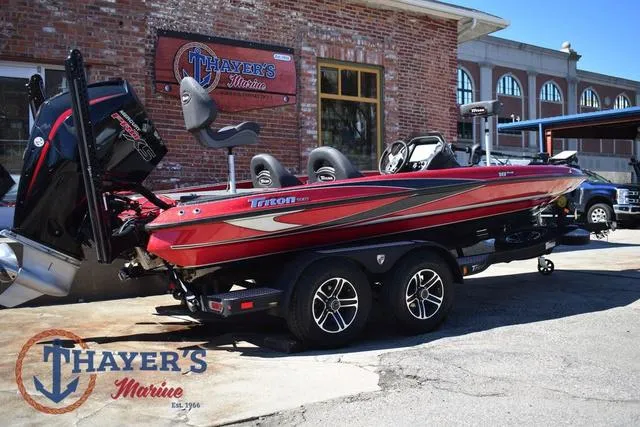 Slide: The Image of 2021 Triton 18 TrX boat in red, parked outside Thayer's Marine. - 3