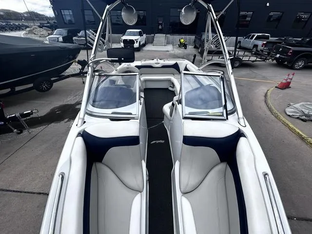 Slide: The Image of 2008 Tigé 24 VE boat interior with white and navy seating, docked outdoors. - 15