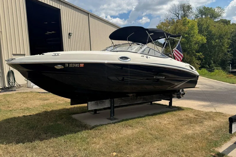 The Image of 2017 Stingray 235 LR boat on display outside a warehouse, with an American flag. - 0