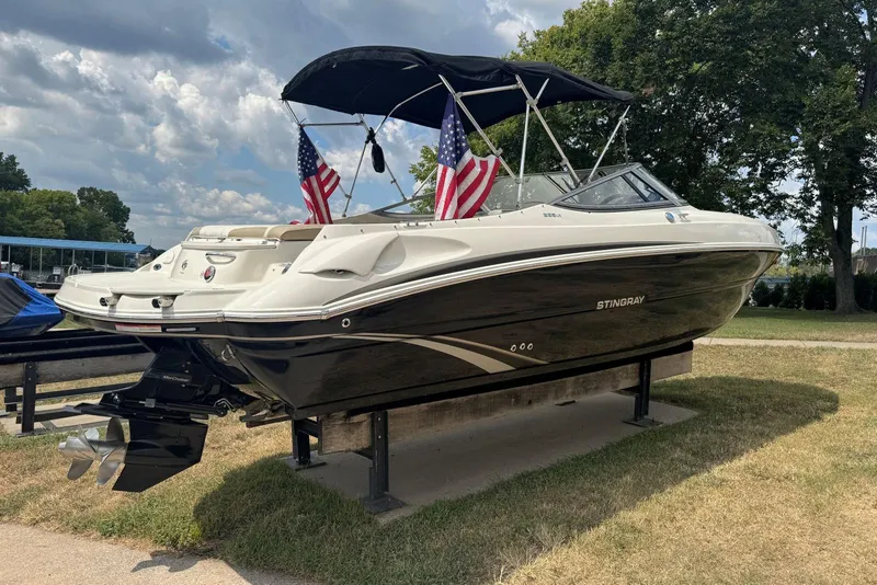 Slide: The Image of 2017 Stingray 235 LR boat with American flags, displayed outdoors on a sunny day. - 2