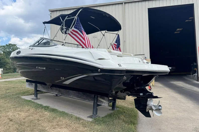 Slide: The Image of 2017 Stingray 235 LR boat with American flags, parked outside a large building. - 4