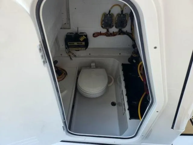 Slide: The Image of 2025 Sportsman Heritage 231 boat interior with compact marine toilet and electrical components. - 14
