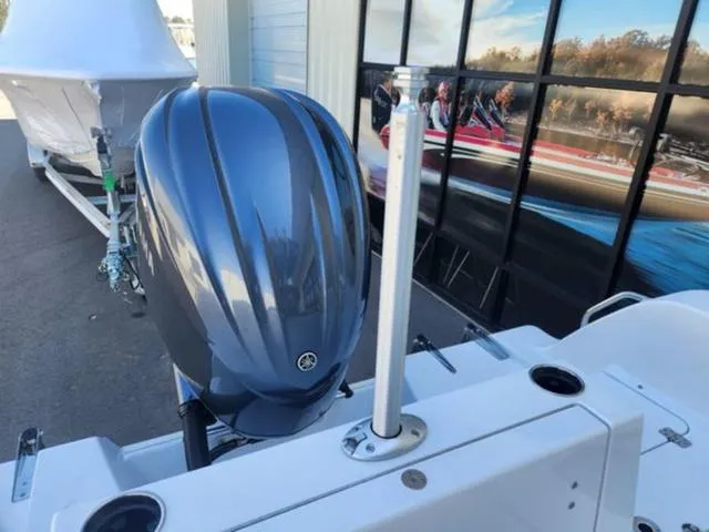 Slide: The Image of 2025 Sportsman Heritage 231 boat with sleek outboard motor, docked near a building. - 18