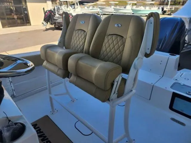 Slide: The Image of 2025 Sportsman Heritage 231 boat seats, featuring tan upholstery and diamond stitching, in a marina setting. - 3
