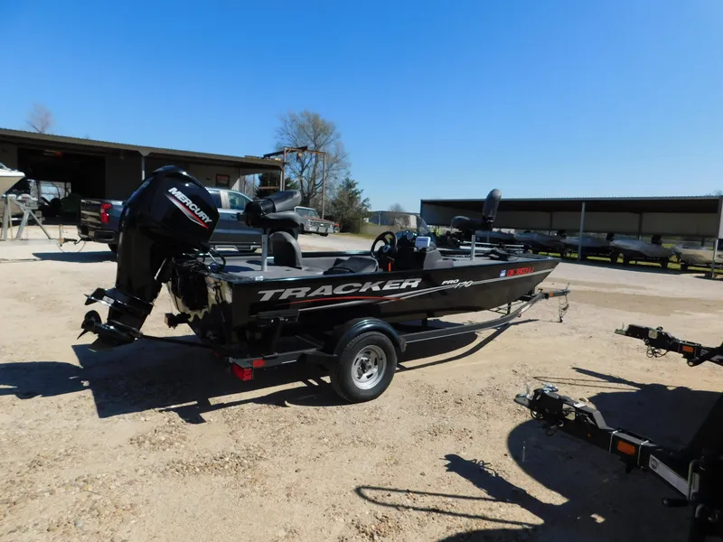 Slide: The Image of 2023 Bass Tracker 170 boat on trailer, parked outdoors under clear blue sky. - 2