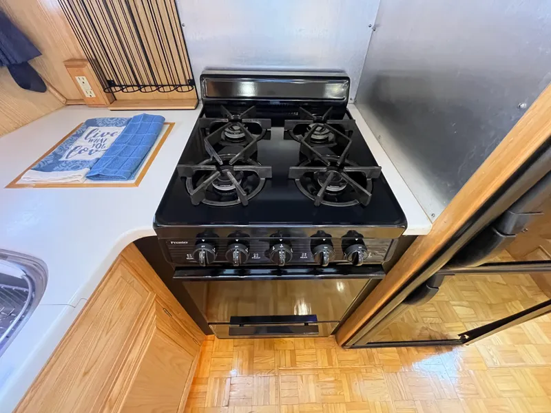 Slide: The Image of 1999 Ocean Alexander Sundeck 460 kitchen with black stove and wooden cabinetry. - 25