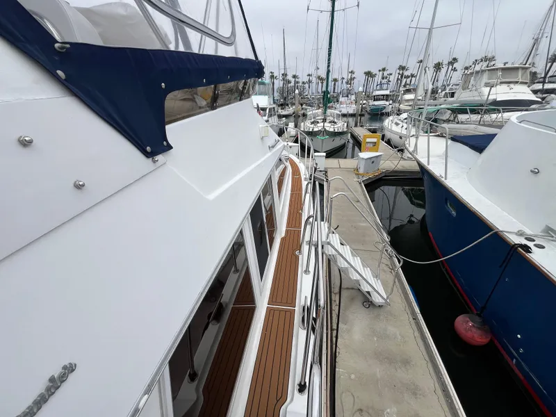 Slide: The Image of 1999 Ocean Alexander Sundeck 460 yacht docked at marina, showcasing sleek design and wooden deck. - 7