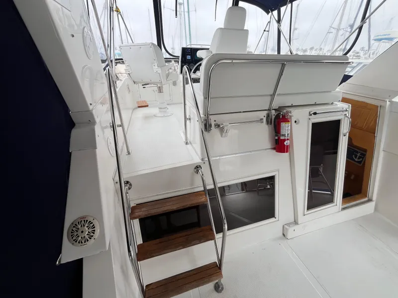 Slide: The Image of Ocean Alexander Sundeck 460 yacht interior, featuring seating, stairs, and a fire extinguisher, 1999 model. - 12