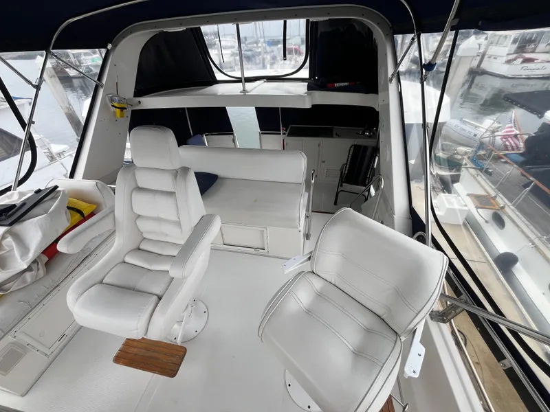 Slide: The Image of 1999 Ocean Alexander Sundeck 460 interior with white seating and helm, docked at marina. - 14