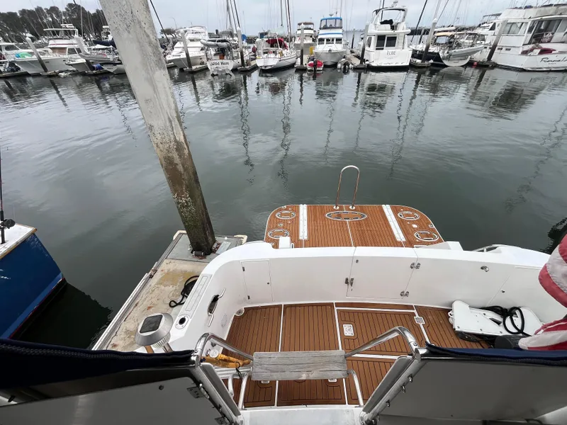 Slide: The Image of Ocean Alexander Sundeck 460, 1999 model, docked at a marina with wooden deck and boats nearby. - 6