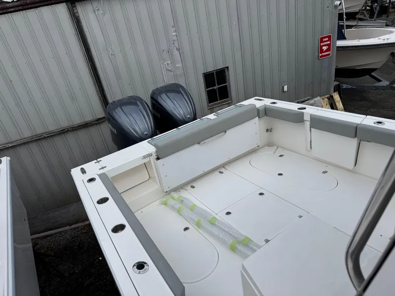 Slide: The Image of 2025 NorthCoast 315 HT boat deck with dual outboard motors, docked near a metal building. - 4