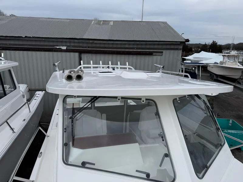 Slide: The Image of 2025 NorthCoast 315 HT boat with sleek design, docked near a metal building. - 6