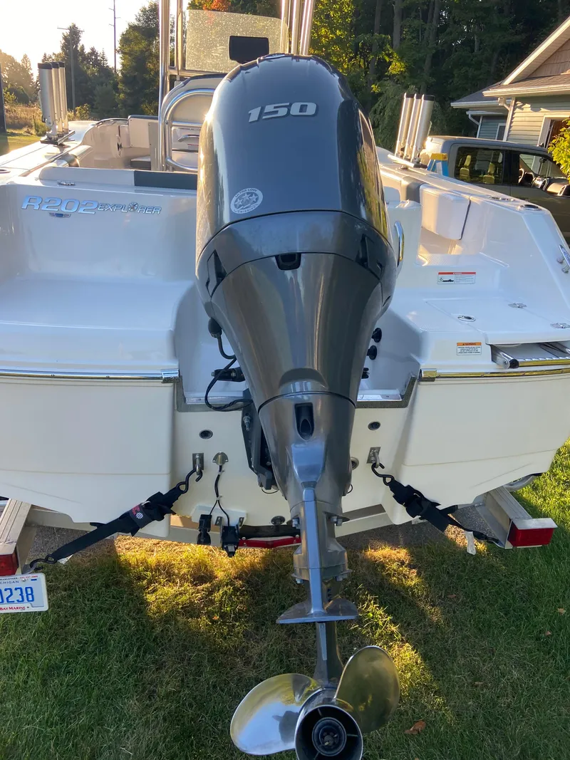 Slide: The Image of 2020 Robalo R202 EX boat with 150 HP outboard motor, parked on grass. - 2