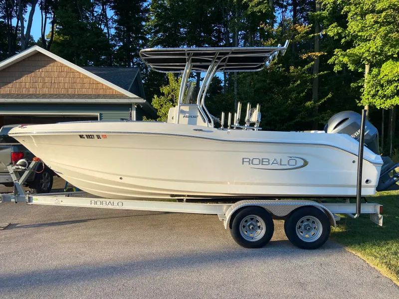 Slide: The Image of 2020 Robalo R202 EX boat on trailer, parked in driveway, surrounded by trees. - 3