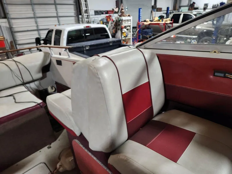 Slide: The Image of 1987 Larson 23 Cuddy Cabin interior with red and white seating in a garage setting. - 6